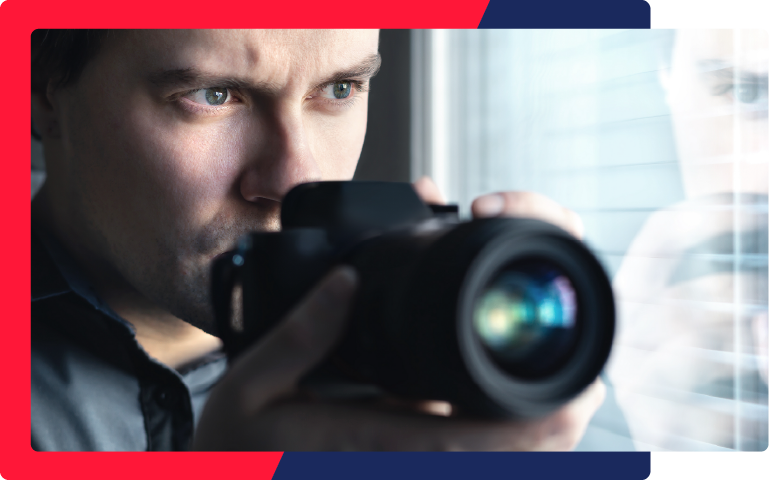A private investigator taking photos out of a window